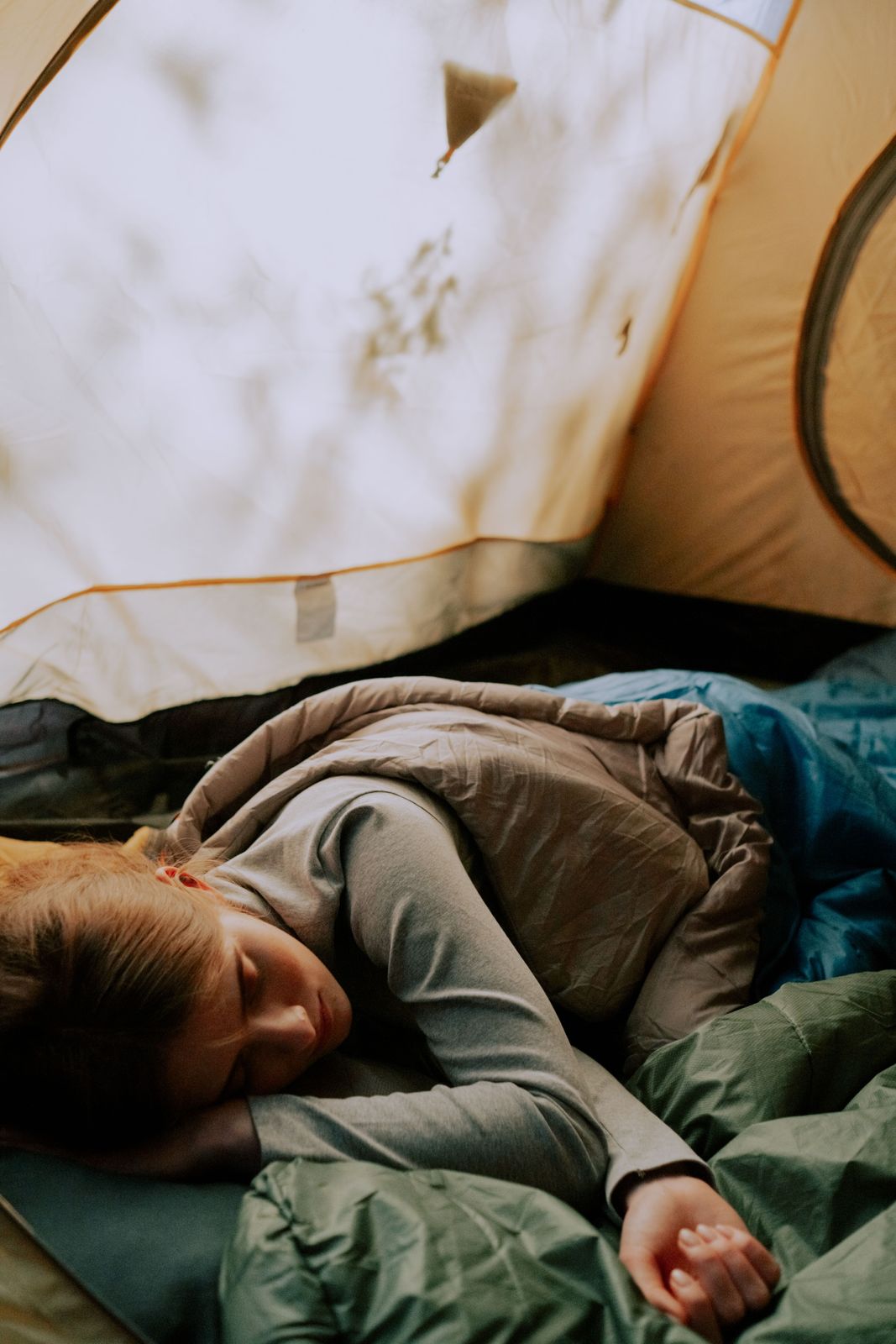 Camper resting in a tent wrapped in a warm sleeping bag
